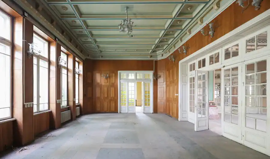 Present-day vacant hall showing the retained functional wall paneling contrasted with the ornate coffered ceiling