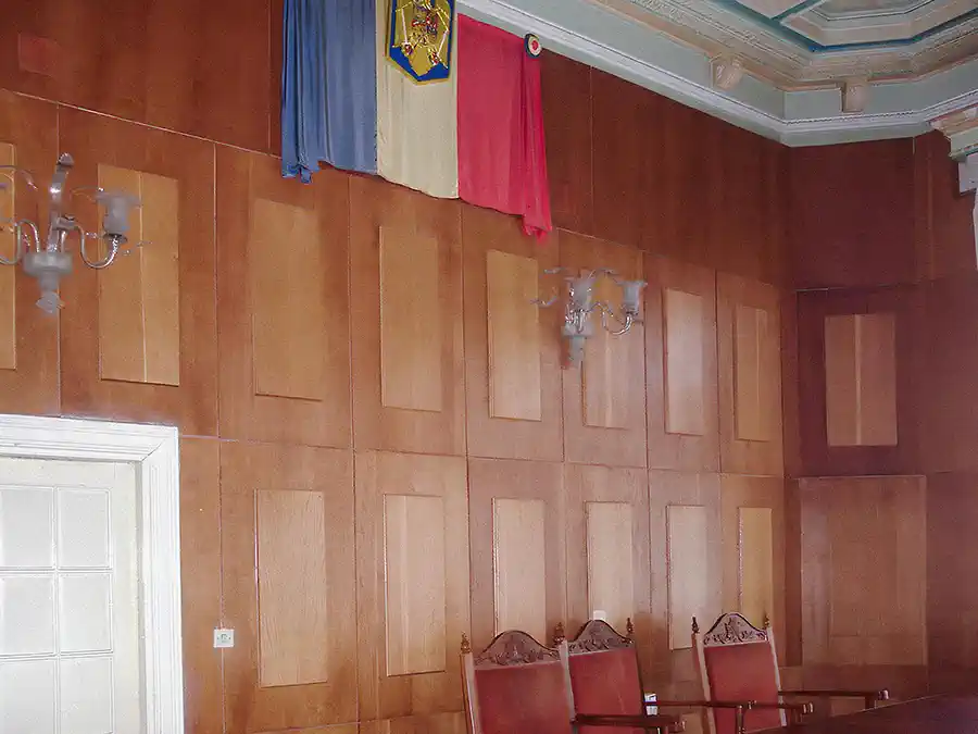 Historic photo of the active courtroom in Casa Băileșteanu with Romanian flag and paneling