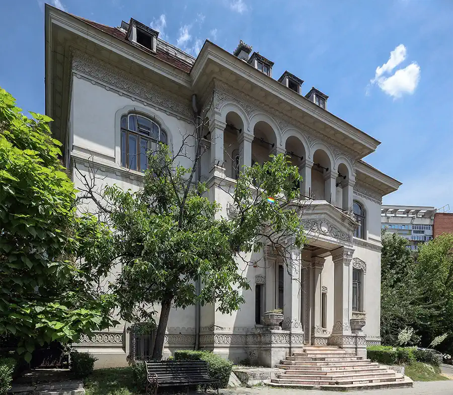 Facade of Casa Băileșteanu in Craiova featuring a round-arched loggia, ornamental stucco friezes and grand entrance stairs