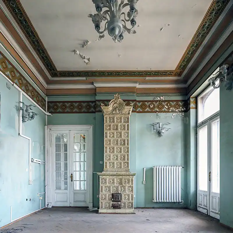 Square view of an interior room in Casa Băileșteanu featuring an ornate tile stove and painted ceiling friezes